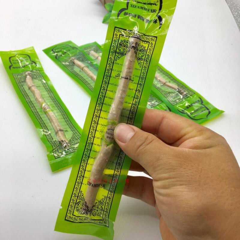 Hand holding a packaged miswak stick
